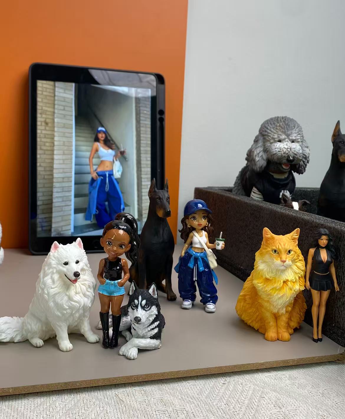 Finished custom people and pet figurines displayed beside their reference photo